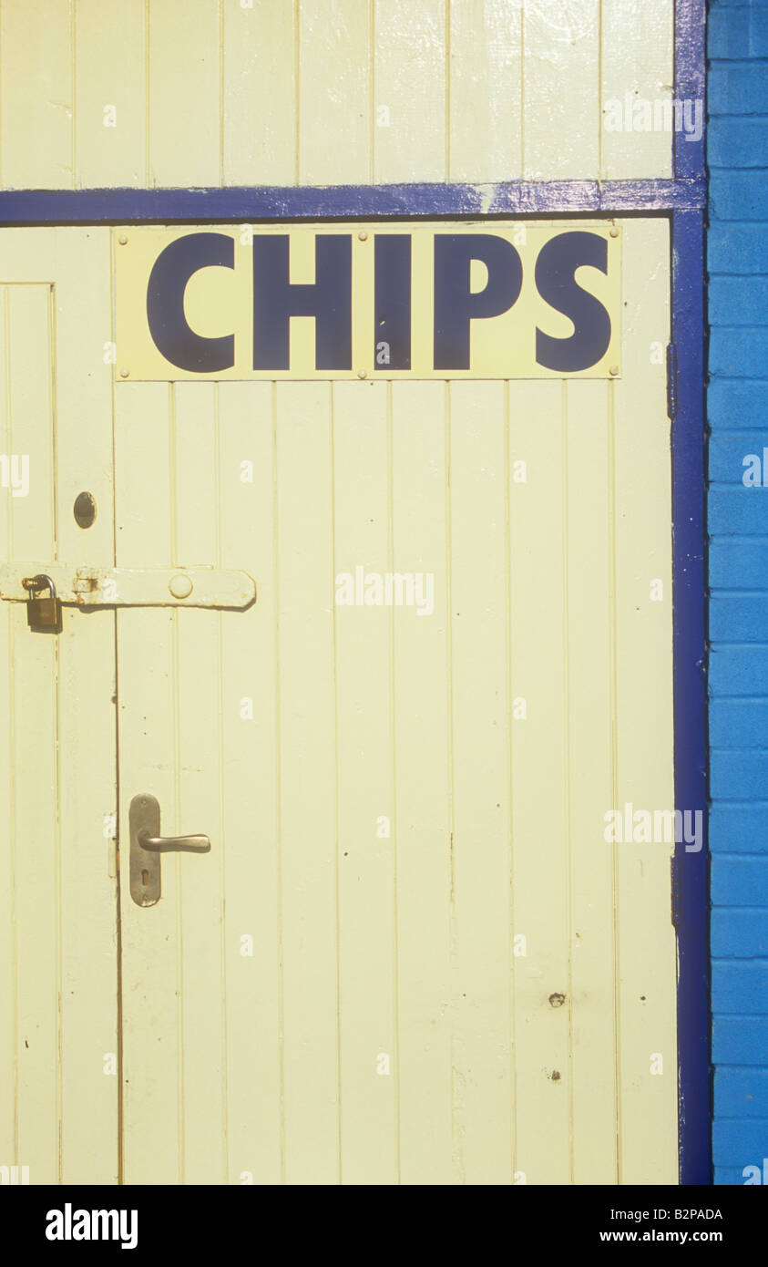Blue and cream sign stating Chips fixed on padlocked cream wooden door with blue doorframe and blue painted brickwall Stock Photo