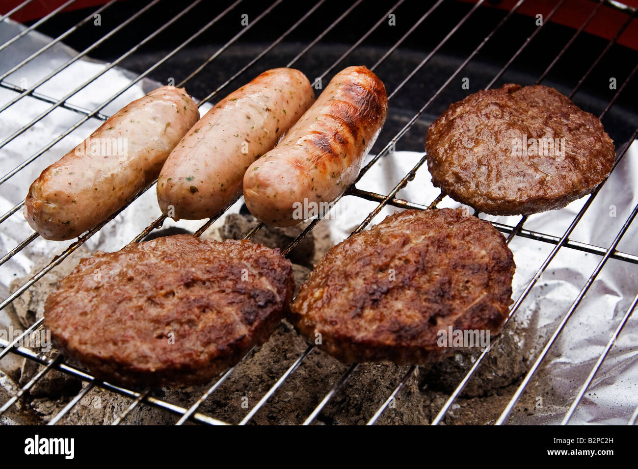 Sausages and beefburgers on a barbecue, UK Stock Photo Alamy