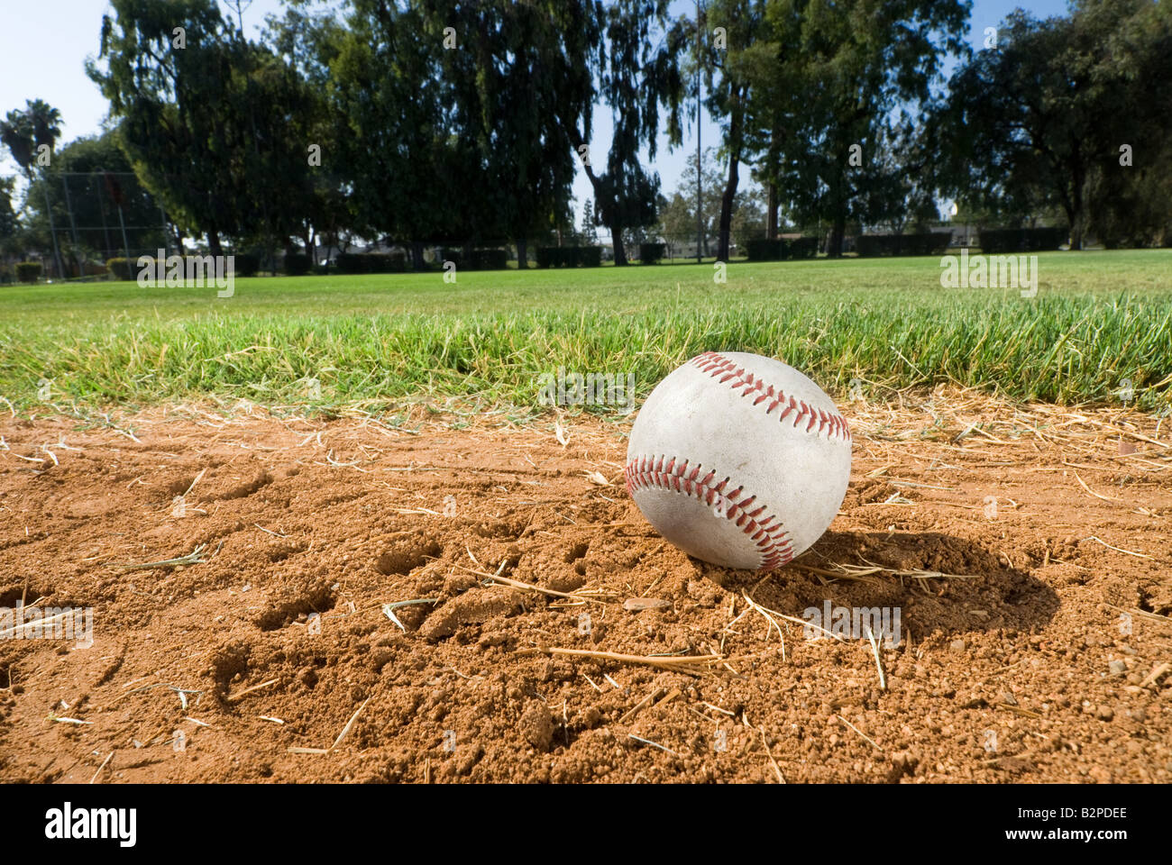 A baseball lies in the dirt during a baseball game peering to the