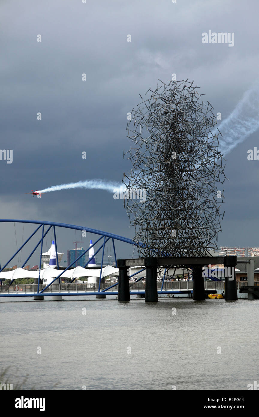 An aerobaticplane flies inverted behind the Antony Gormley sculpture 'Quantum Cloud’ Stock Photo
