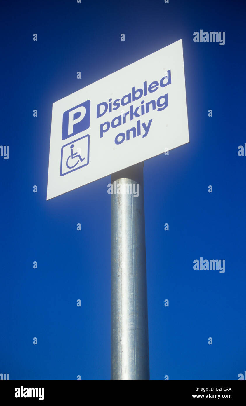 White and blue sign on silver pole with deep blue sky and symbol of person in wheelchair stating P Disabled parking only Stock Photo