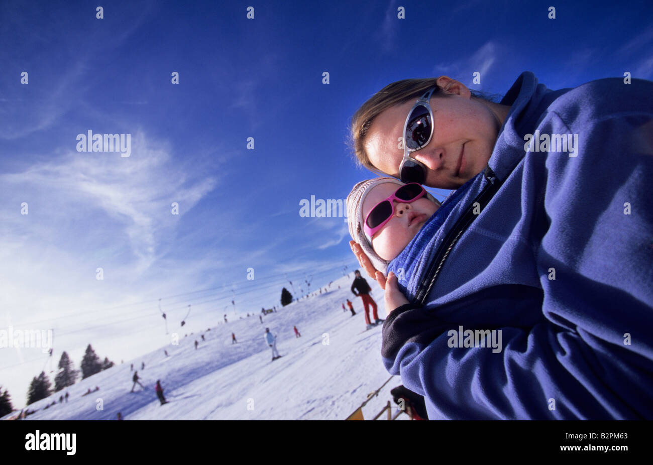 Mother and baby daughter with sunglasses enjoying a sunny day at a Ski Resort Feldberg Germany January 2008 Stock Photo