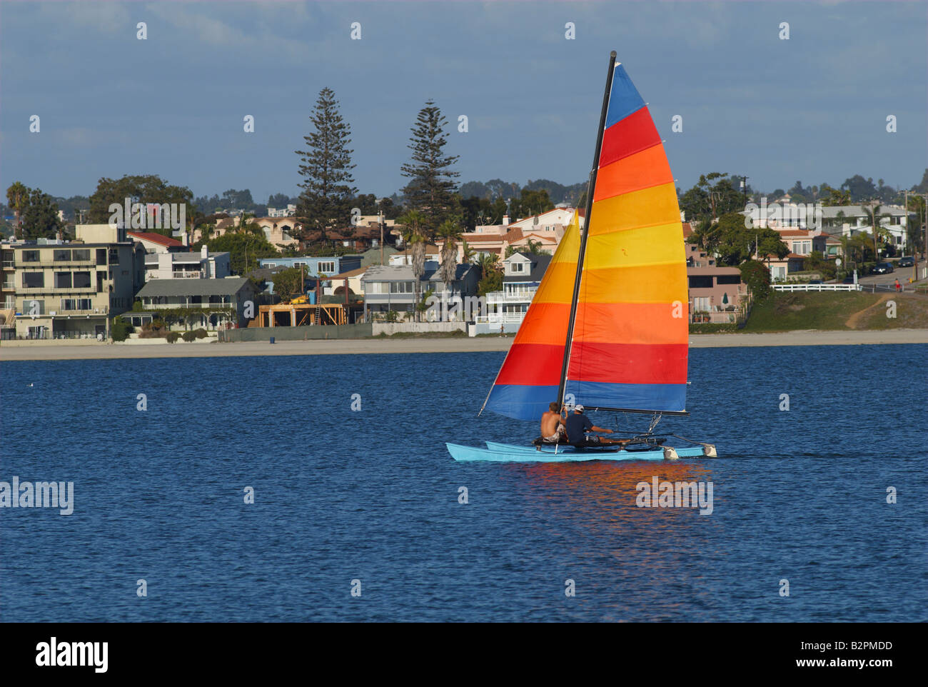 Two men are sailing a yacht with colorful sail in Mission Bay San Diego