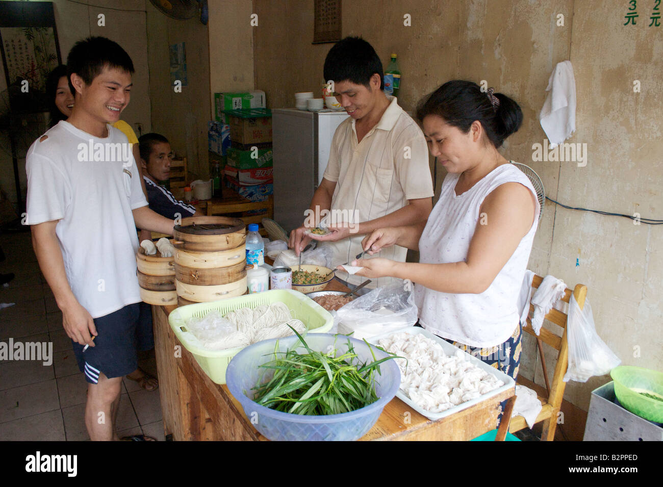 A couple make small dumplings for steaming at a small restaurant in Yangshuo Guangxi China Stock Photo