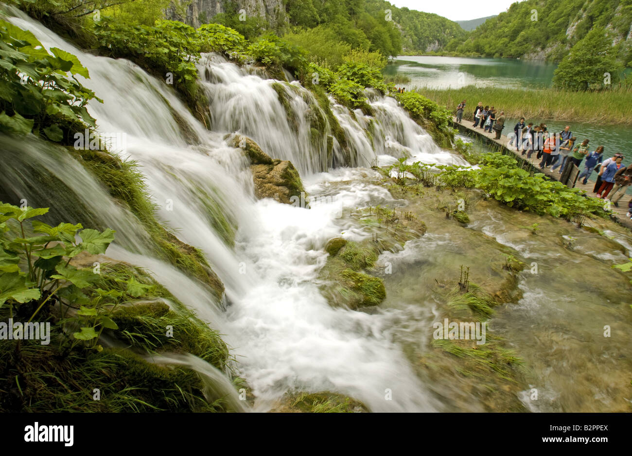 Plitvice Lakes National Park waterfalls between lakes with young visitors on boardwalk Stock Photo