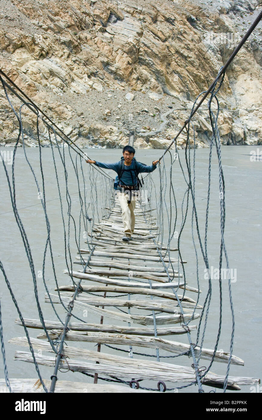 Hiker Crossing a Suspension Bridge Near Passu in Hunza Valley in