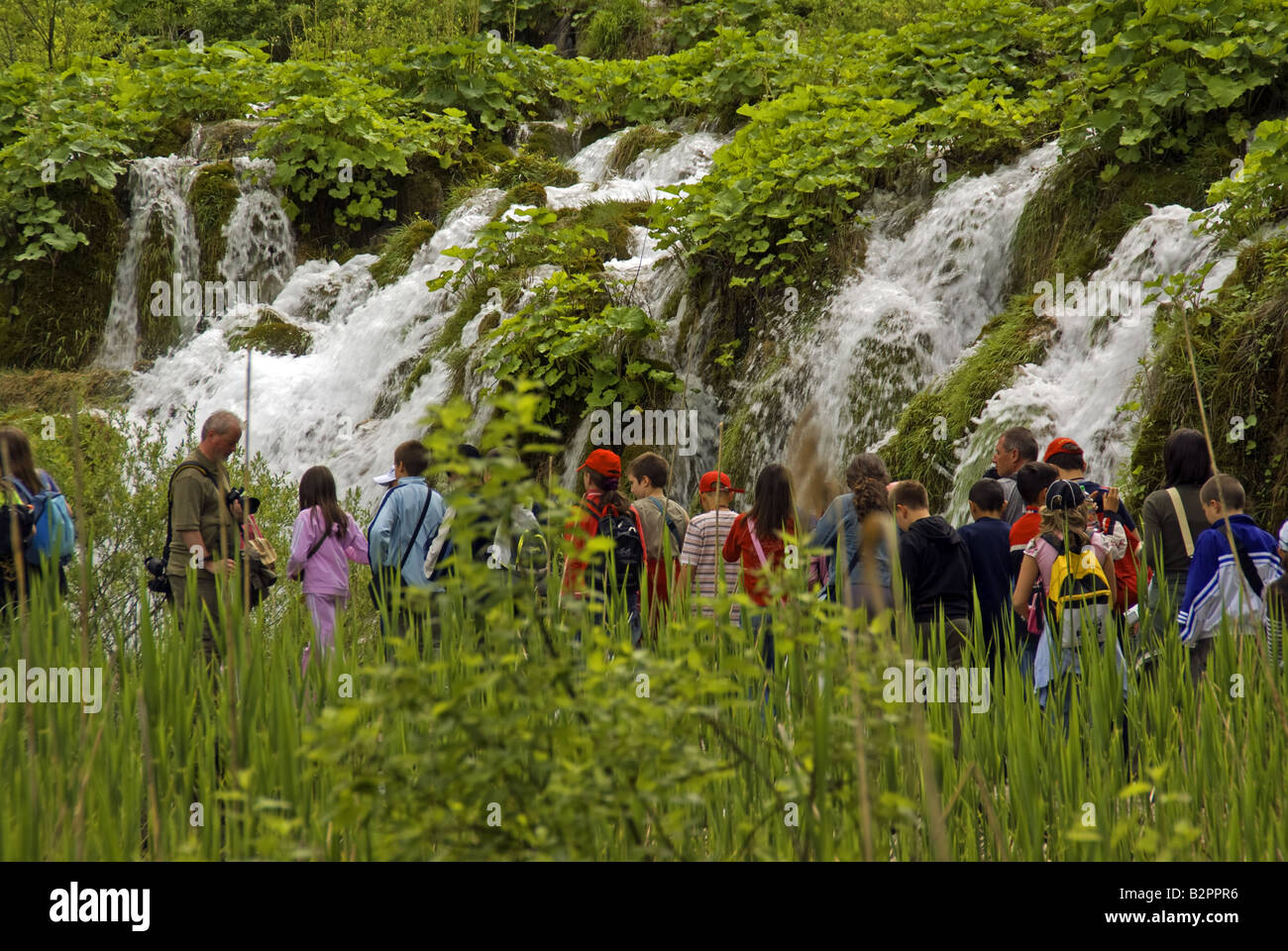 Plitvice Lakes National Park waterfalls between lakes with young visitors on boardwalk Stock Photo