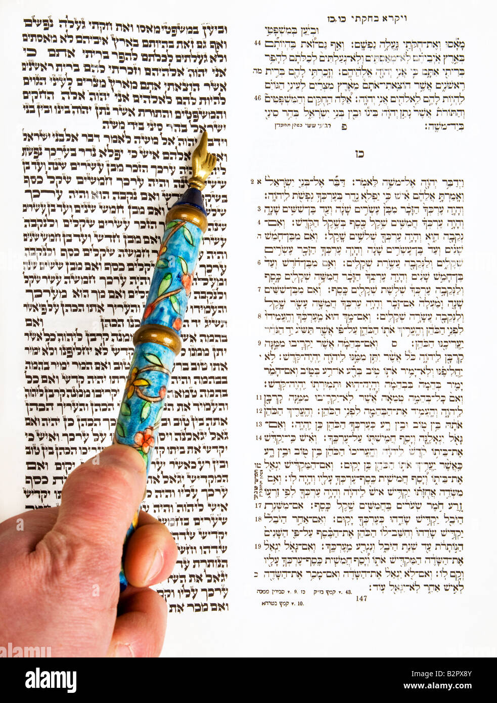 Bar Mitzvah reading Torah in tikkun book with Hebrew on right side and text as it appears in Torah on left using a yad pointer. Stock Photo
