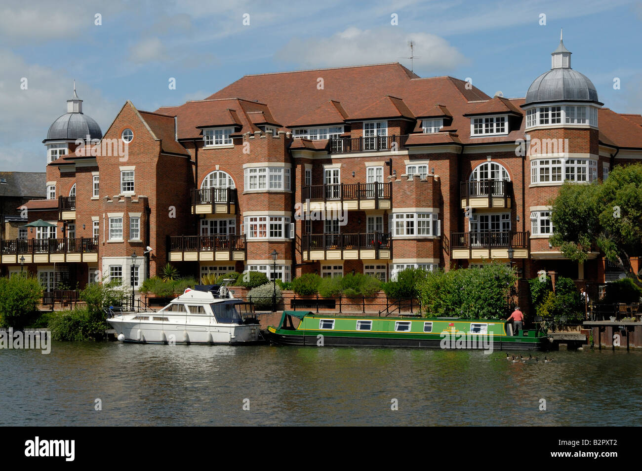 Narrowboat and motor cruiser moored on River Thames before riverside apartments at Eton, Berkshire, England Stock Photo