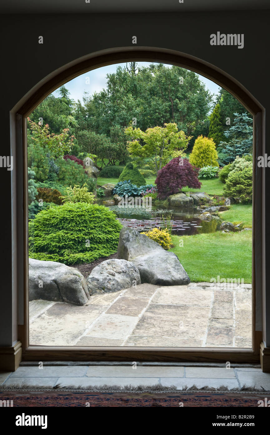 View from the window to the garden with patio, pond, shrubs & trees in garden design by Bahaa Seedhom North Yorkshire England UK Stock Photo
