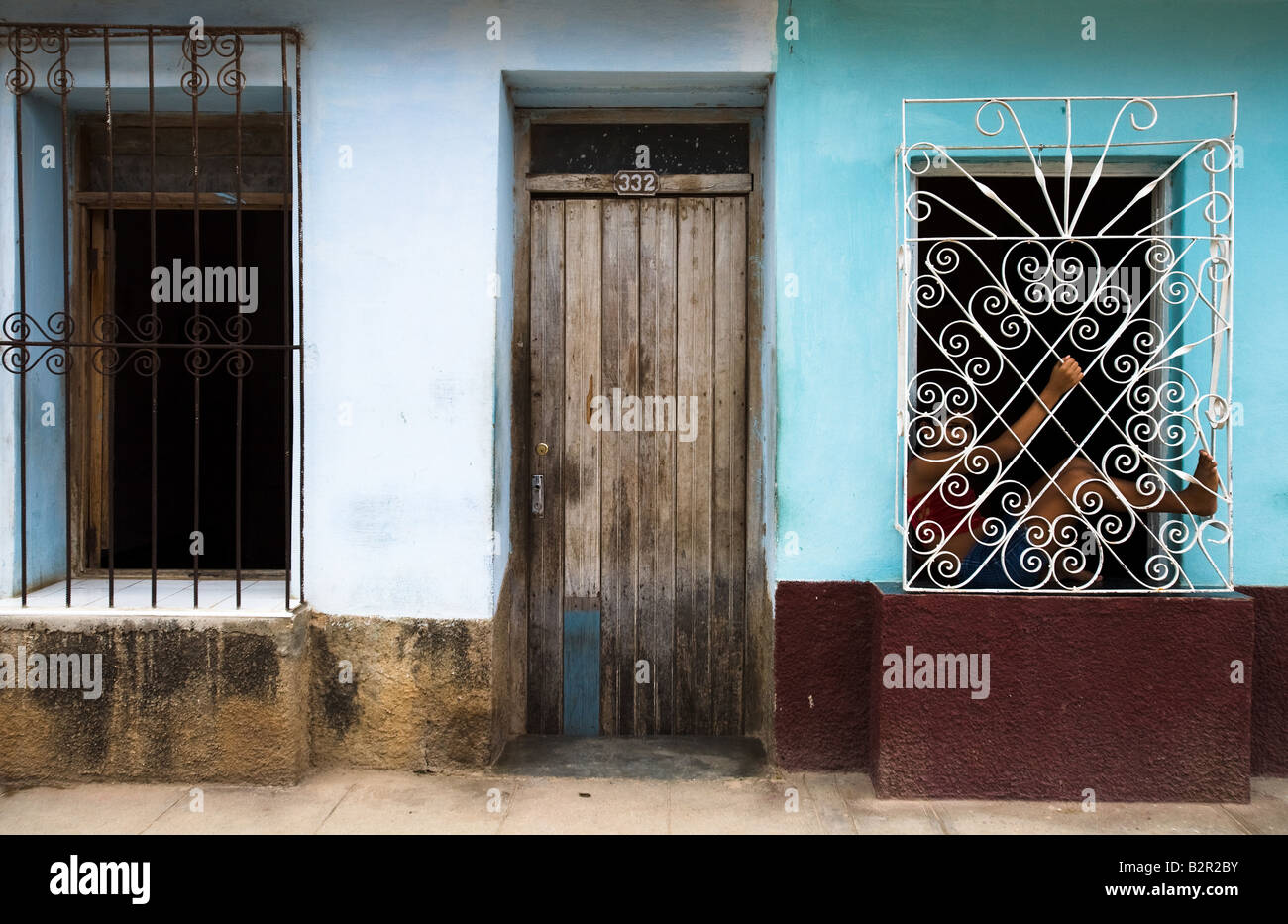 A girl sits in the window of her home in Trinidad Cuba Stock Photo