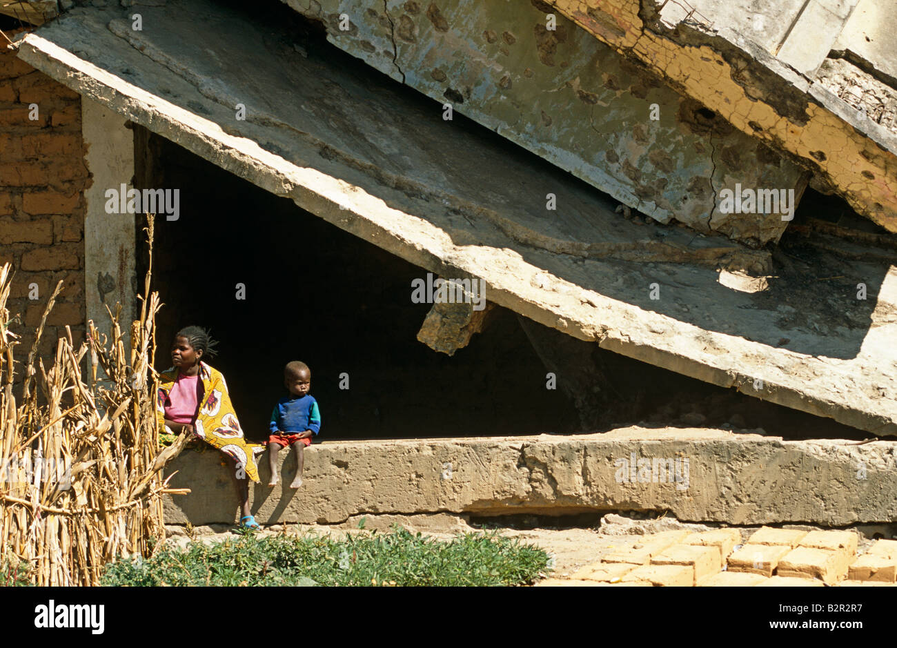 Mother and son sitting on destroyed building, Luanda, Angola Stock Photo