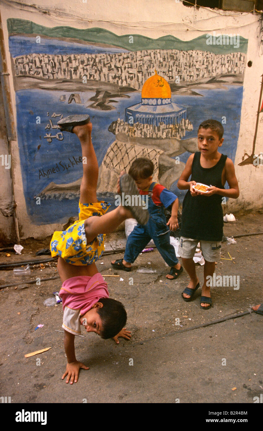Boys playing by graffiti of mosque on wall, Palestinian Shatila Refugee Camp, Beirut, Lebanon Stock Photo