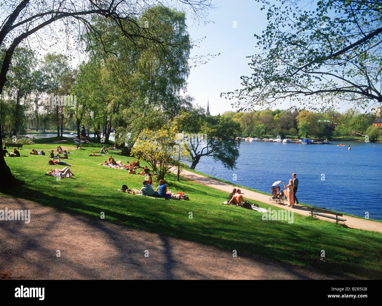 Families and visitors on grass sharing romantic summer picnics and sunbathing at Djurgarden in Stockholm Stock Photo