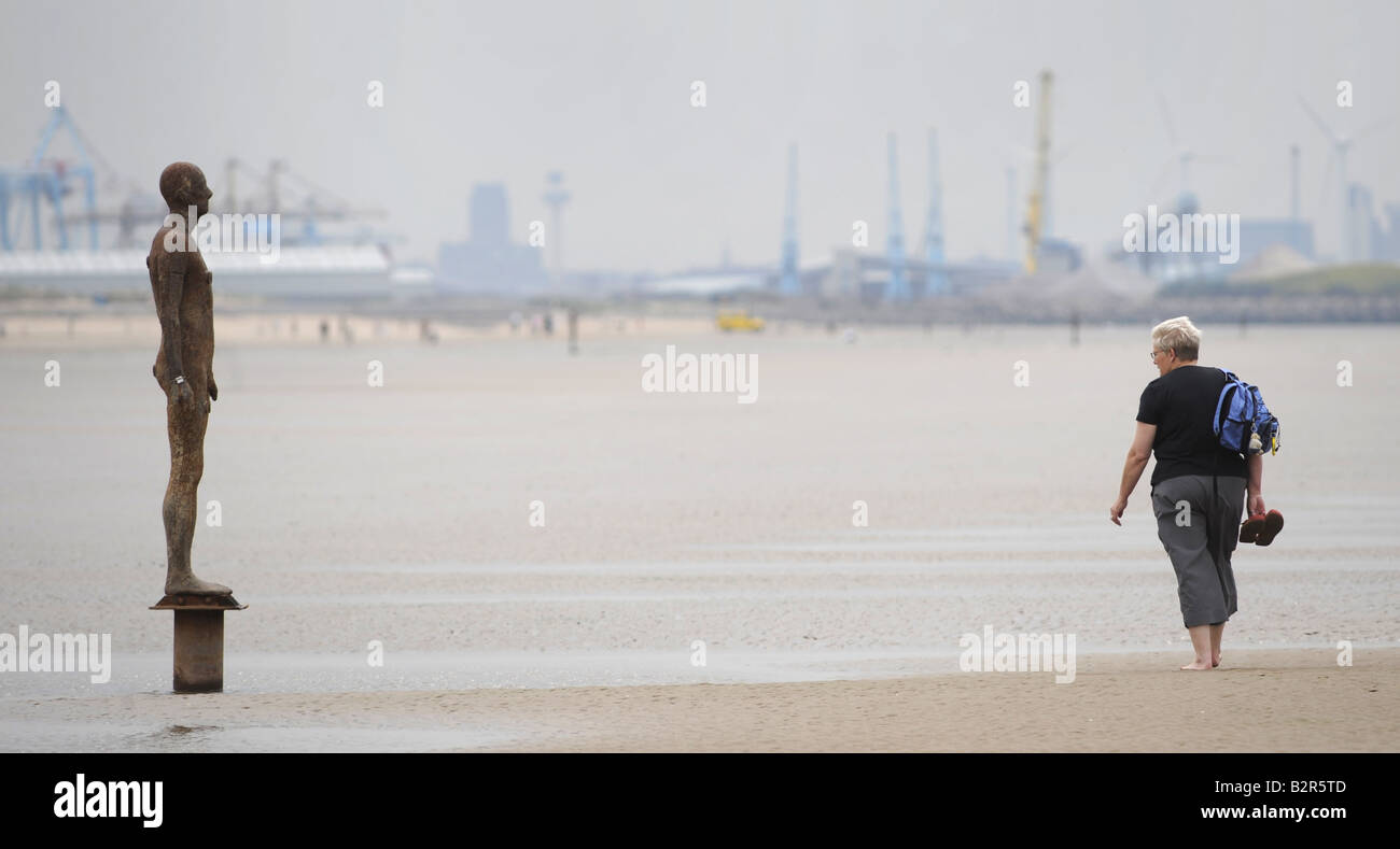 A WALKER LOOKS AT ONE OF THE IRON MEN STATUES ON CROSBY BEACH NEAR LIVERPOOL CREATED BY ARTIST ANTONY GORMLEY,UK,ENGLAND. Stock Photo
