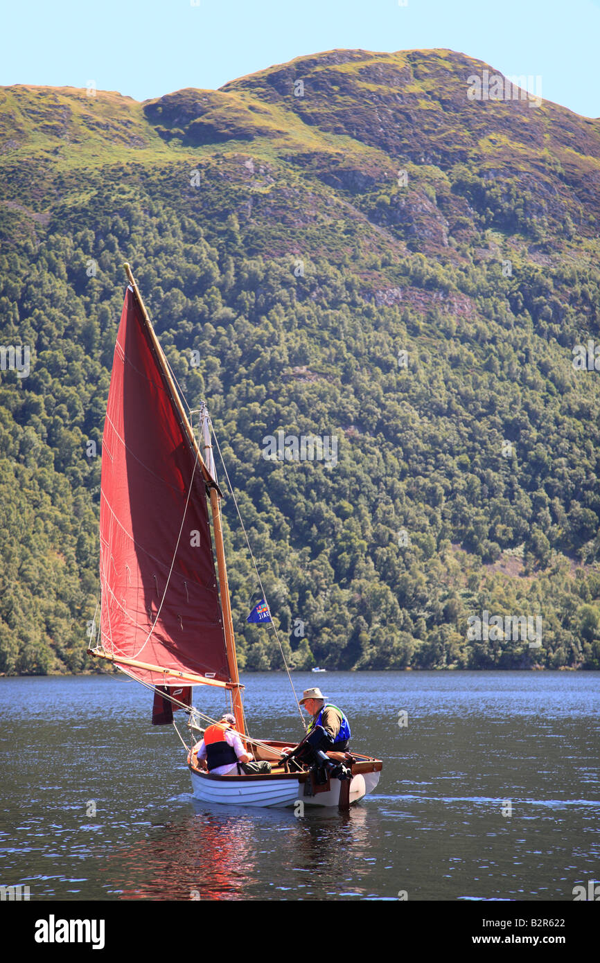 Retired couple sailing a white sailing boat on Ullswater, The Lake District National Park, Cumbria, England, United Kingdom. Stock Photo