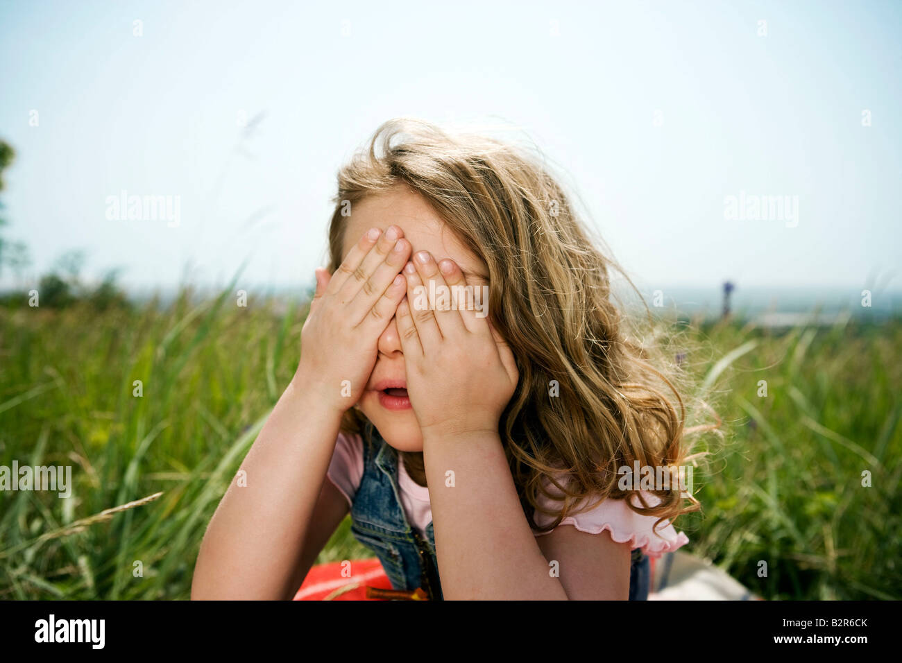 Girl hiding behind hands Stock Photo Alamy