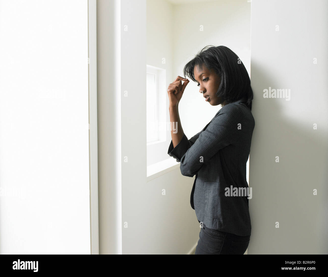 Woman leaning against a wall Stock Photo - Alamy