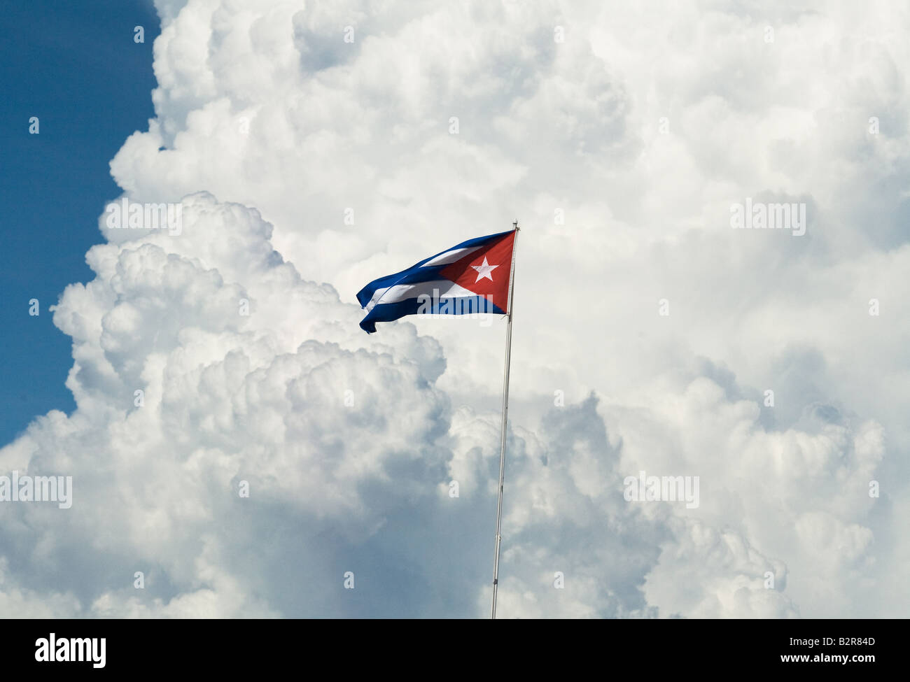 A Cuban flag flies against a backdrop of large cloud formations at Marina Marlin near playa Ancon Cuba Stock Photo