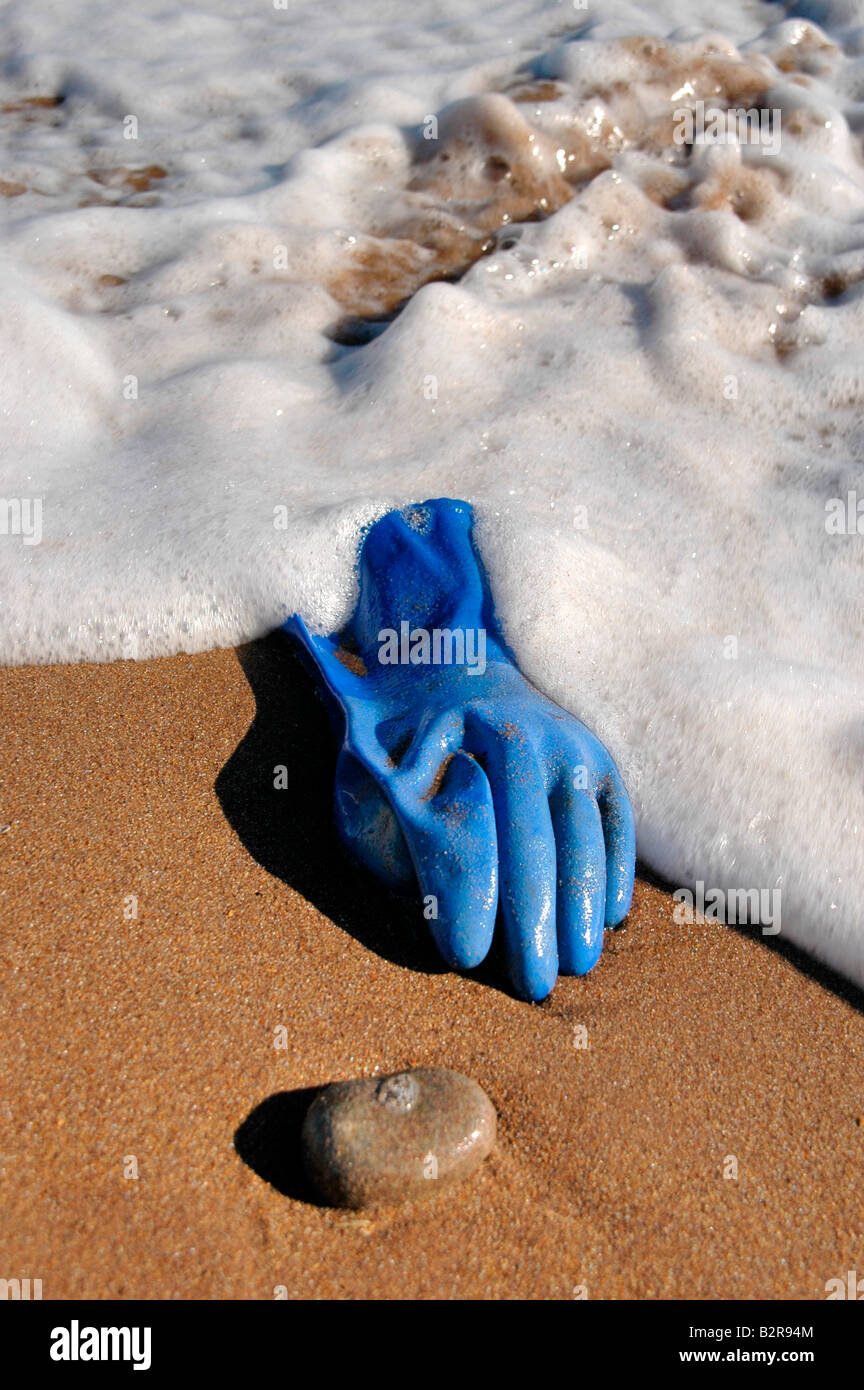 A blue rubber glove washed up onto  the beach. Stock Photo