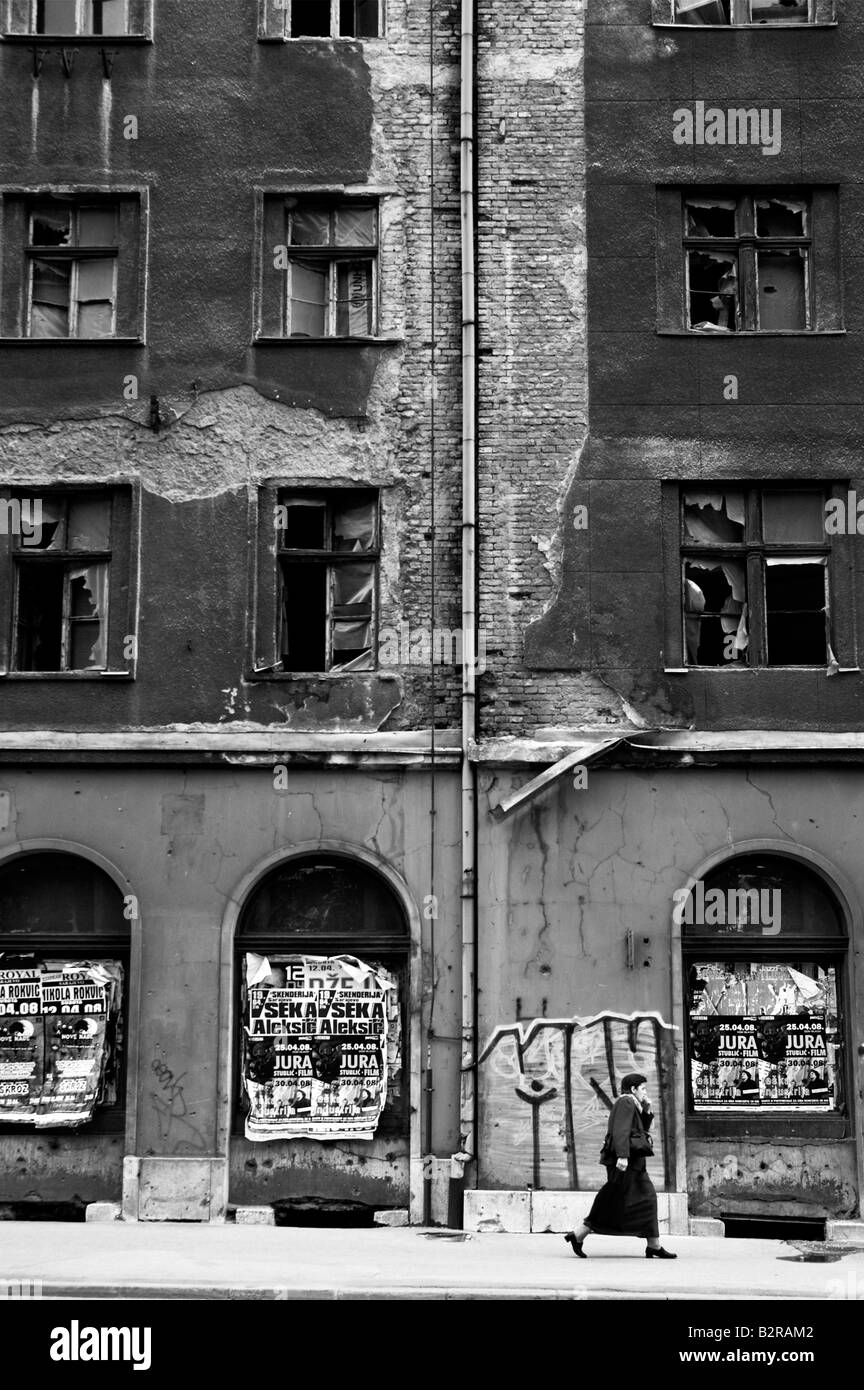 Woman walking past an abandoned building in central Sarajevo Bosnia Herzegovina Europe Stock Photo