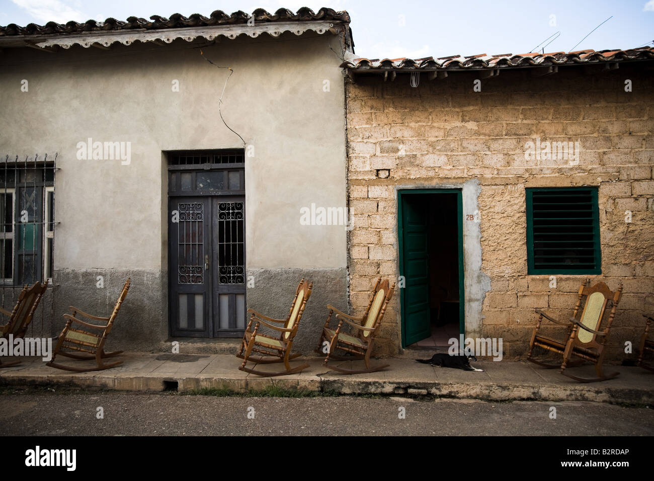 Rocking chairs lined up on the sidewalk outside a home in Remedios, Cuba Stock Photo