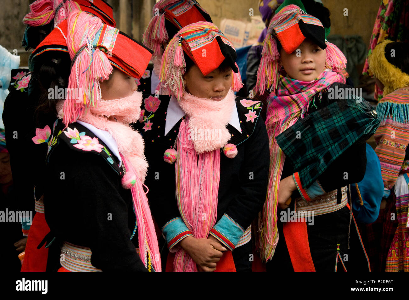 Three red Dao tribal girls wearing traditional headdress and costume smiling at a market Northern Vietnam Stock Photo