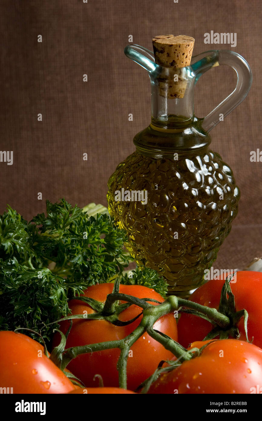 Still life of Italian ingredients including extra virgin olive oil red ripe tomatoes on the vine and parsley  Stock Photo