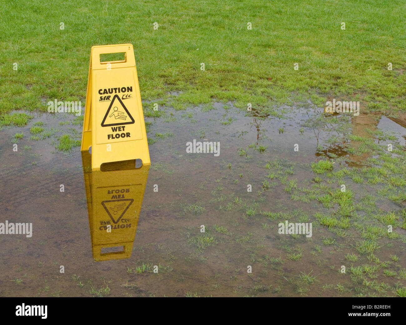 WARNING SIGN IN PUDDLE IN PARK CHELTENHAM ENGLAND Stock Photo