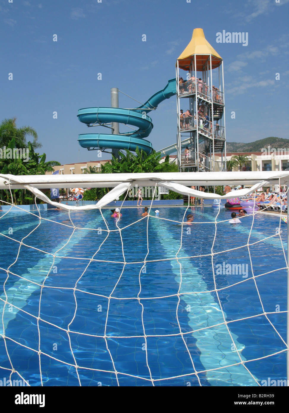 Water slide and swimming pool seen through water polo goal, holiday complex, Turkey Stock Photo