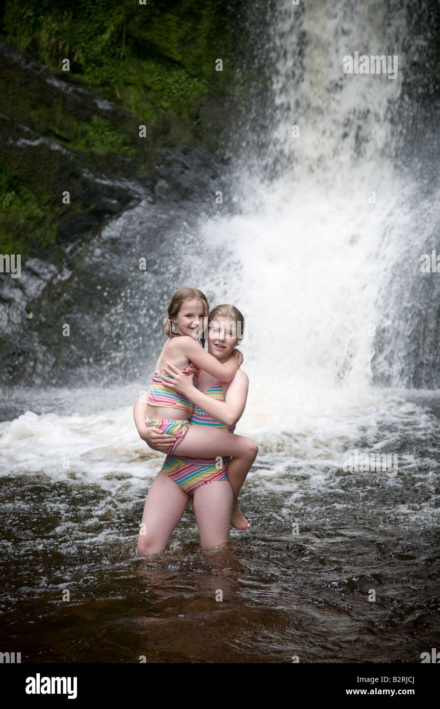 two young girls (sisters) wild swimming at Pistyll Rhaeadr waterfall the tallest in Wales Llanrhaeadr ym Mochnant Powys Wales UK Stock Photo