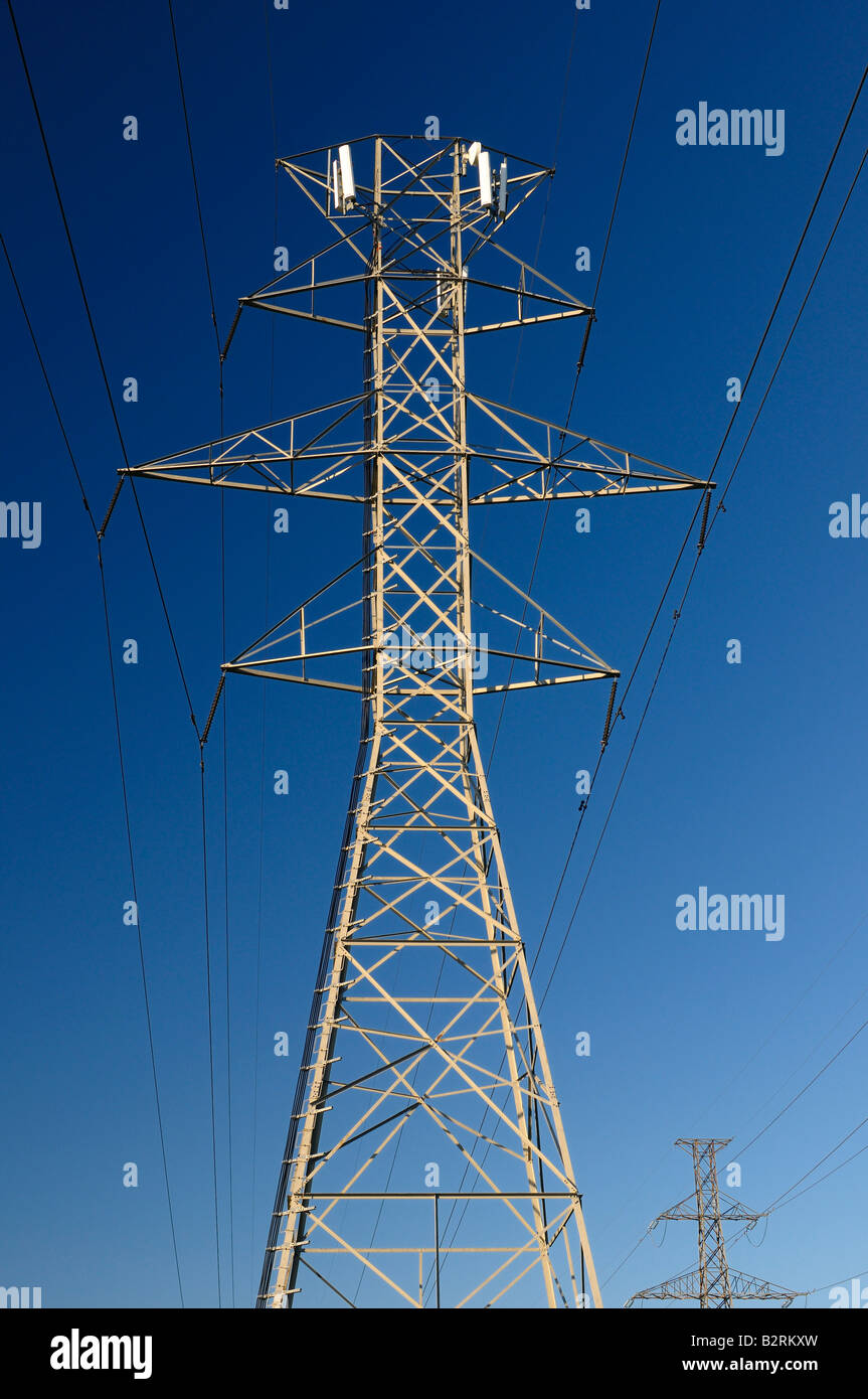 Cell phone transmitters piggybacking on a steel frame hydro tower power line against a blue sky Toronto Stock Photo