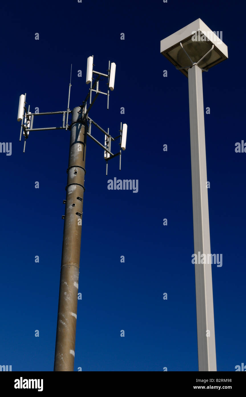 Cell phone communications tower against a blue sky with a lamp post Stock Photo