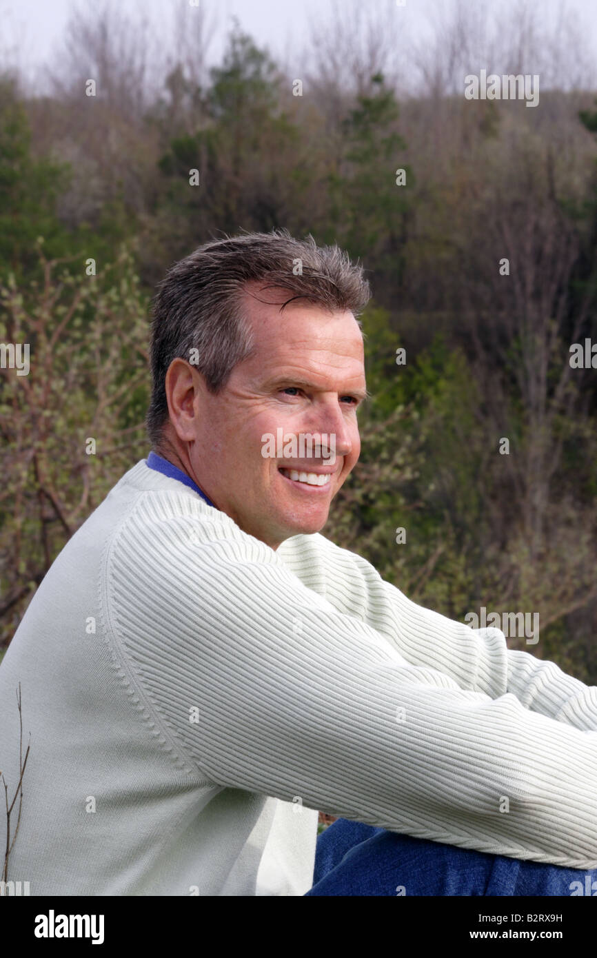 Middle aged Caucasian man smiling in forested valley in early spring Stock Photo