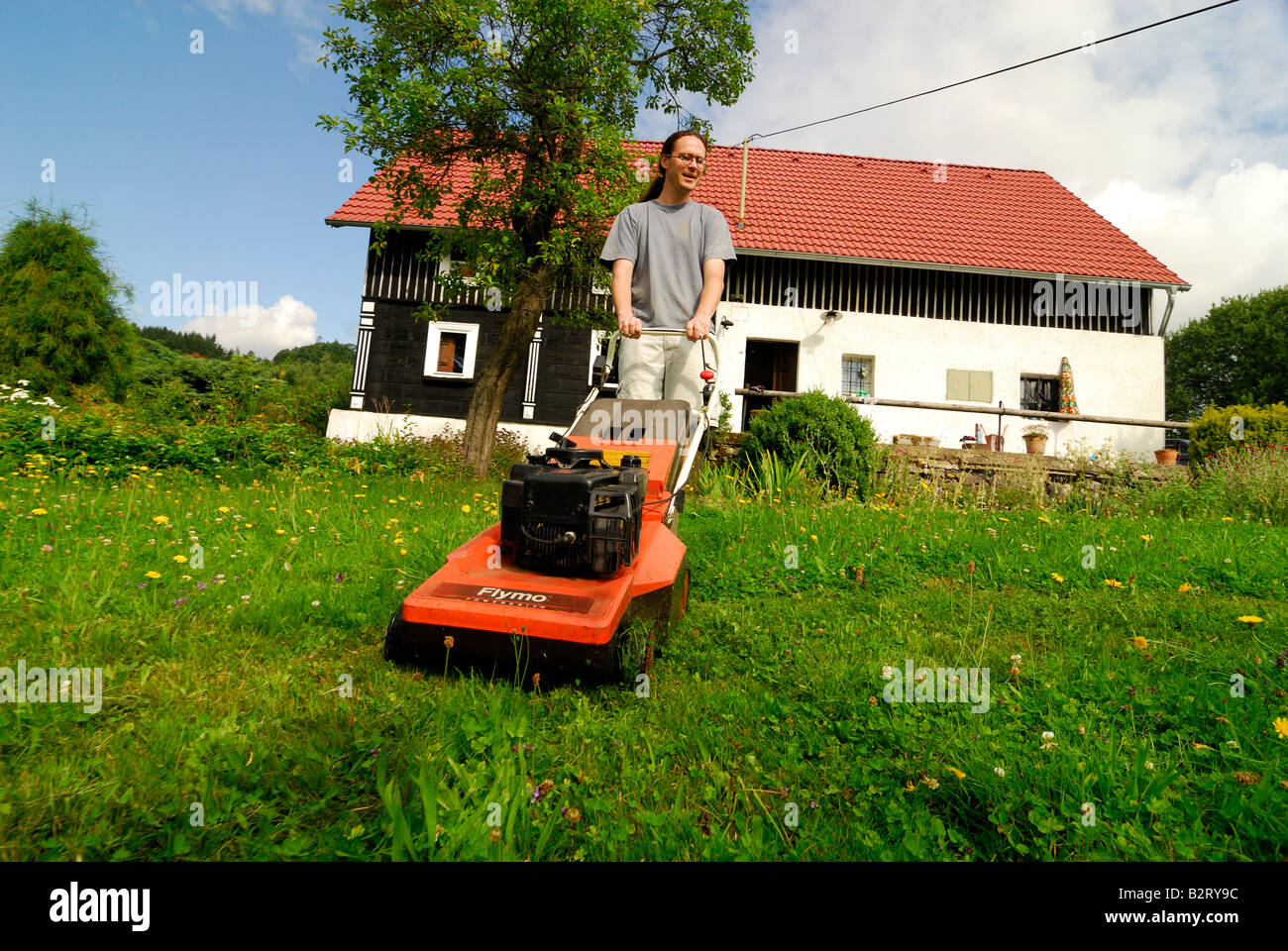 man father while mowing the lawn green grass garden Stock Photo