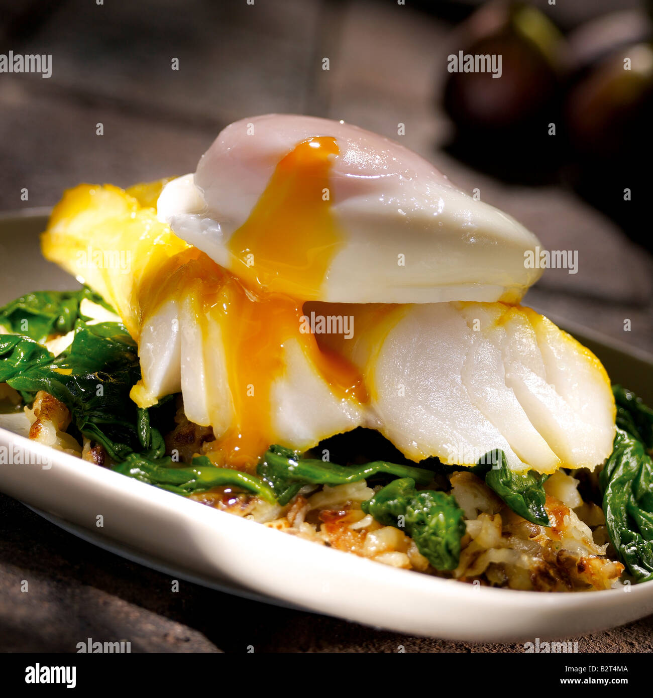 smoked cod on bed of green leaves with poached egg Stock Photo