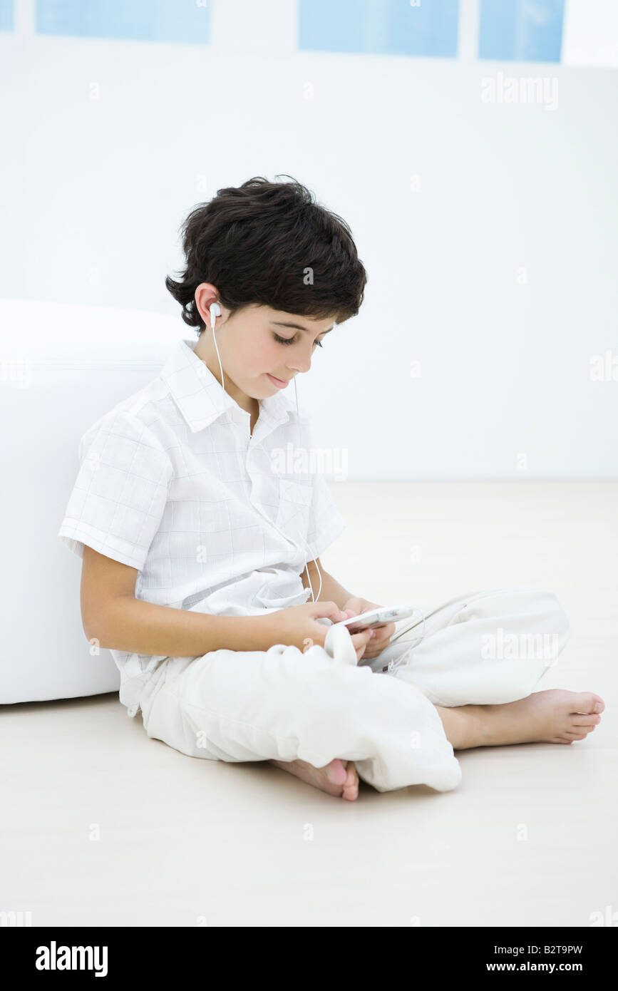 Boy sitting cross-legged on the floor, listening to MP3 player Stock Photo  - Alamy