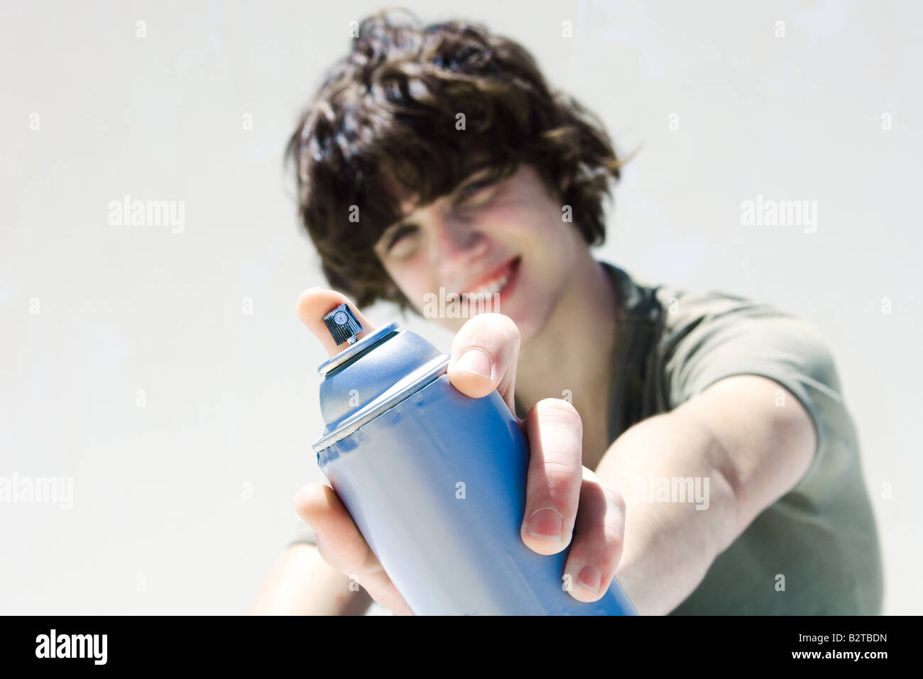 Teenage boy pointing can of spray paint at camera, focus on the foreground Stock Photo