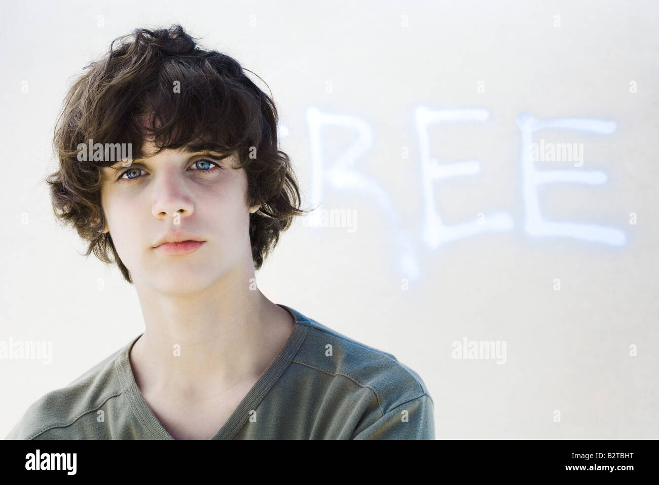 Teenage boy looking at camera, in front of graffiti Stock Photo