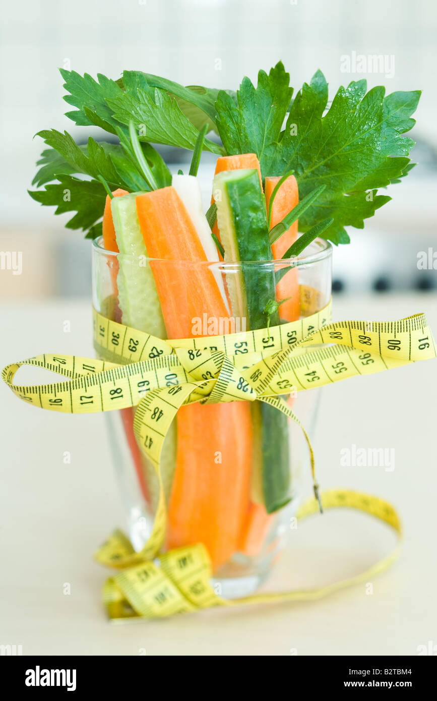 Measuring tape tied in a bow around a glass filled with fresh vegetables Stock Photo