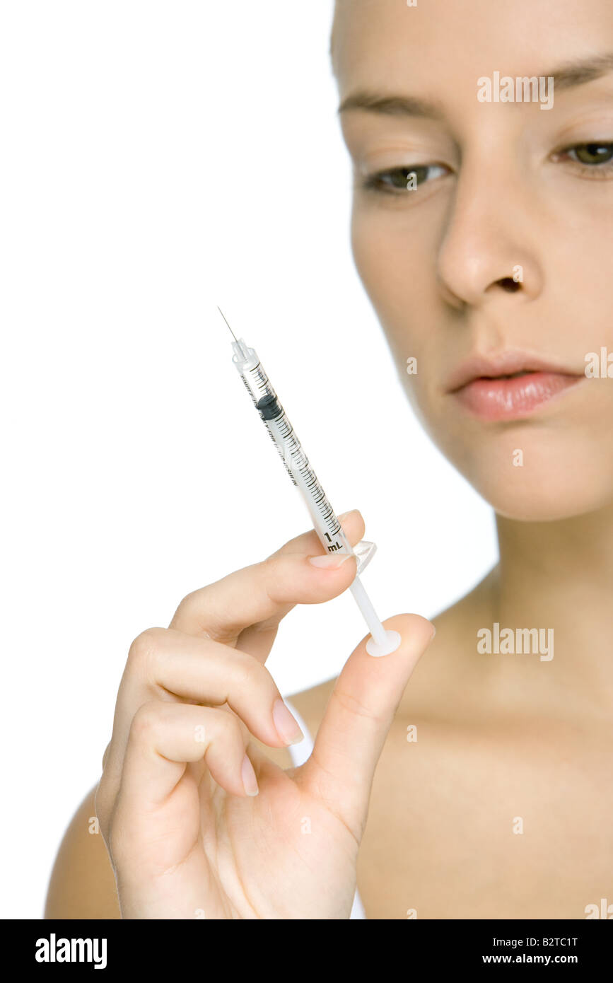 Young woman looking at syringe, cropped view Stock Photo