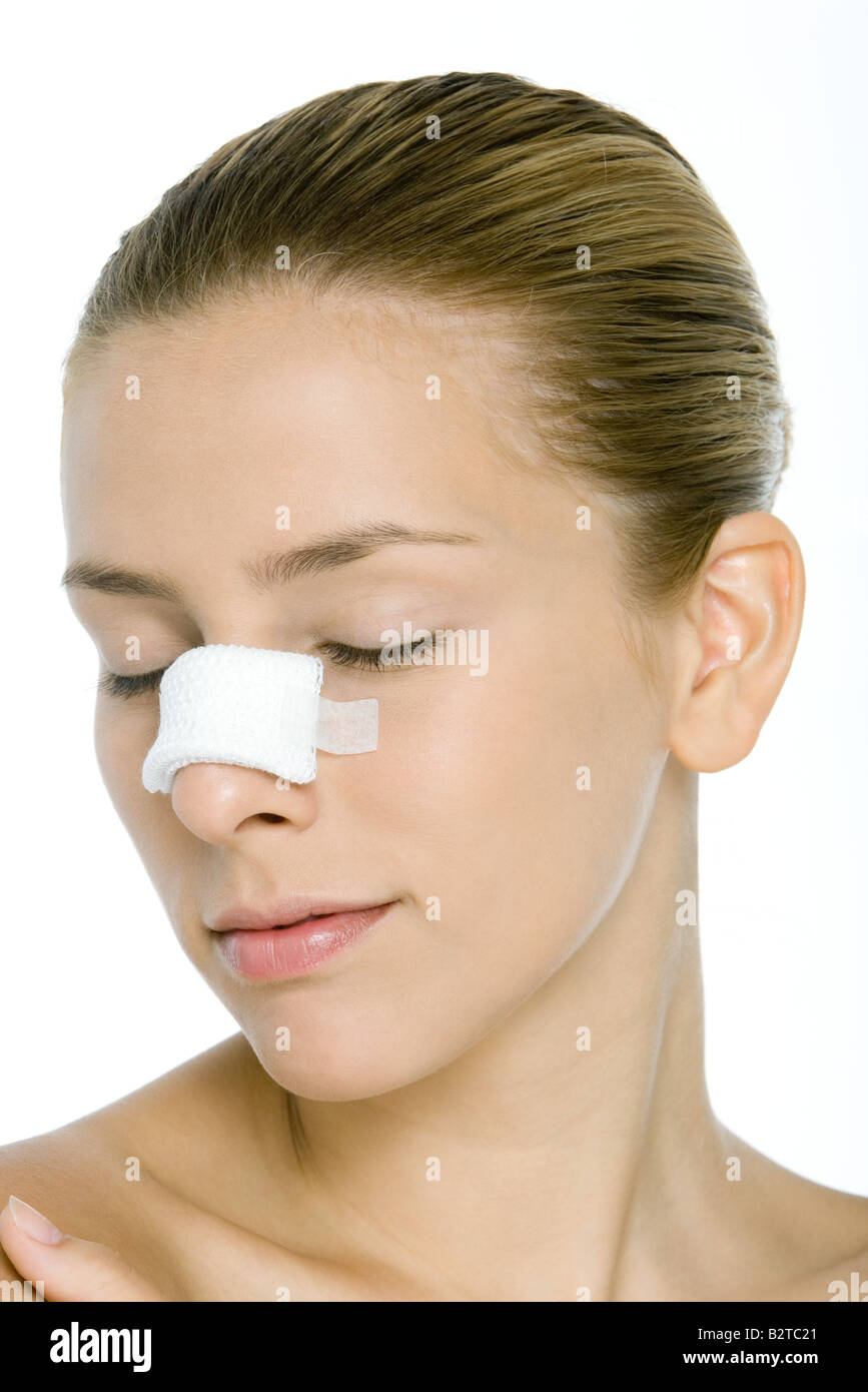 Young woman with bandaged nose, eyes closed Stock Photo