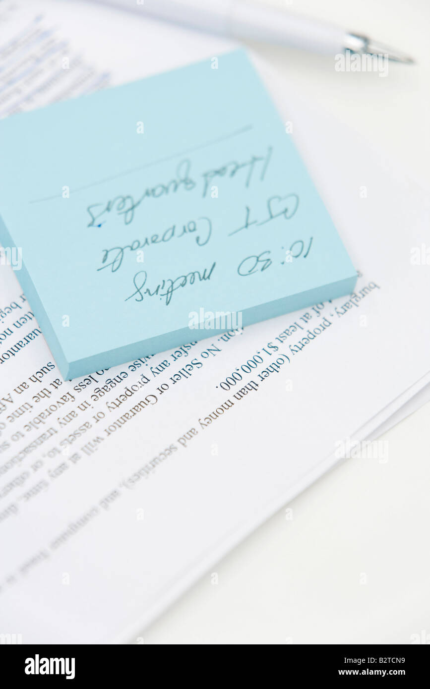 Message written on adhesive note and document, close-up Stock Photo