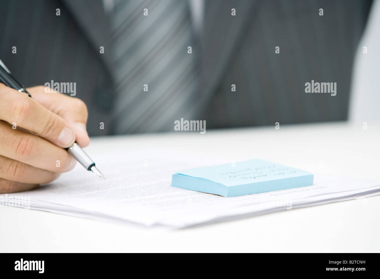 Man with adhesive note and document, holding pen, cropped view Stock Photo