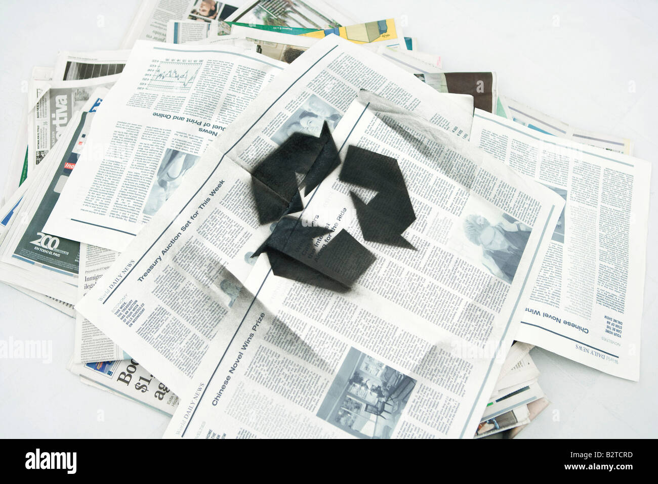 Pile of newspapers spray painted with recycling symbol Stock Photo