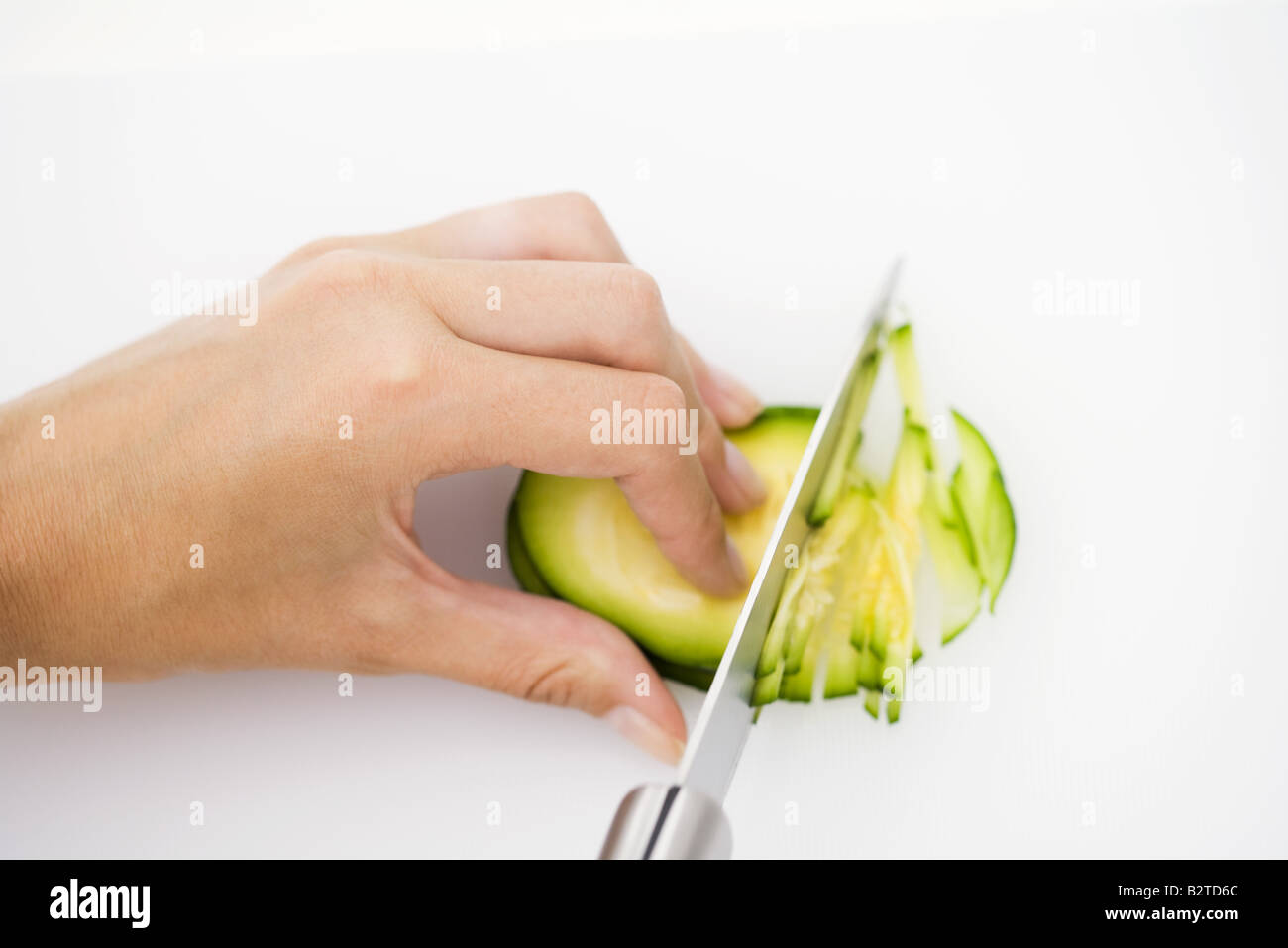 Knife cutting summer squash (zapallito redondo), hand holding in place