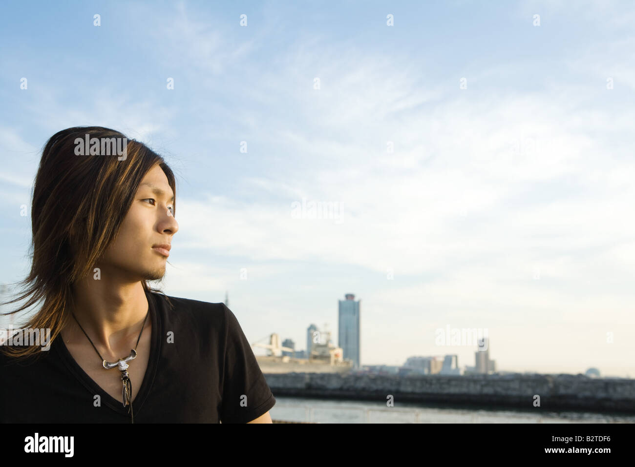 Young Japanese man at waterfront, looking at view, profile Stock Photo