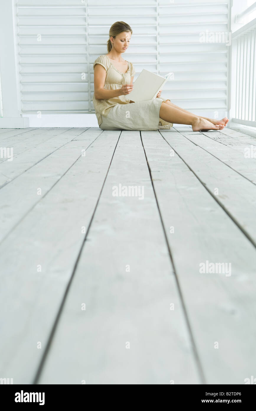 Woman sitting on porch reading book, low angle view Stock Photo