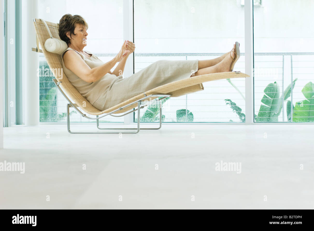 Woman reclining on lounge chair, side view Stock Photo Alamy