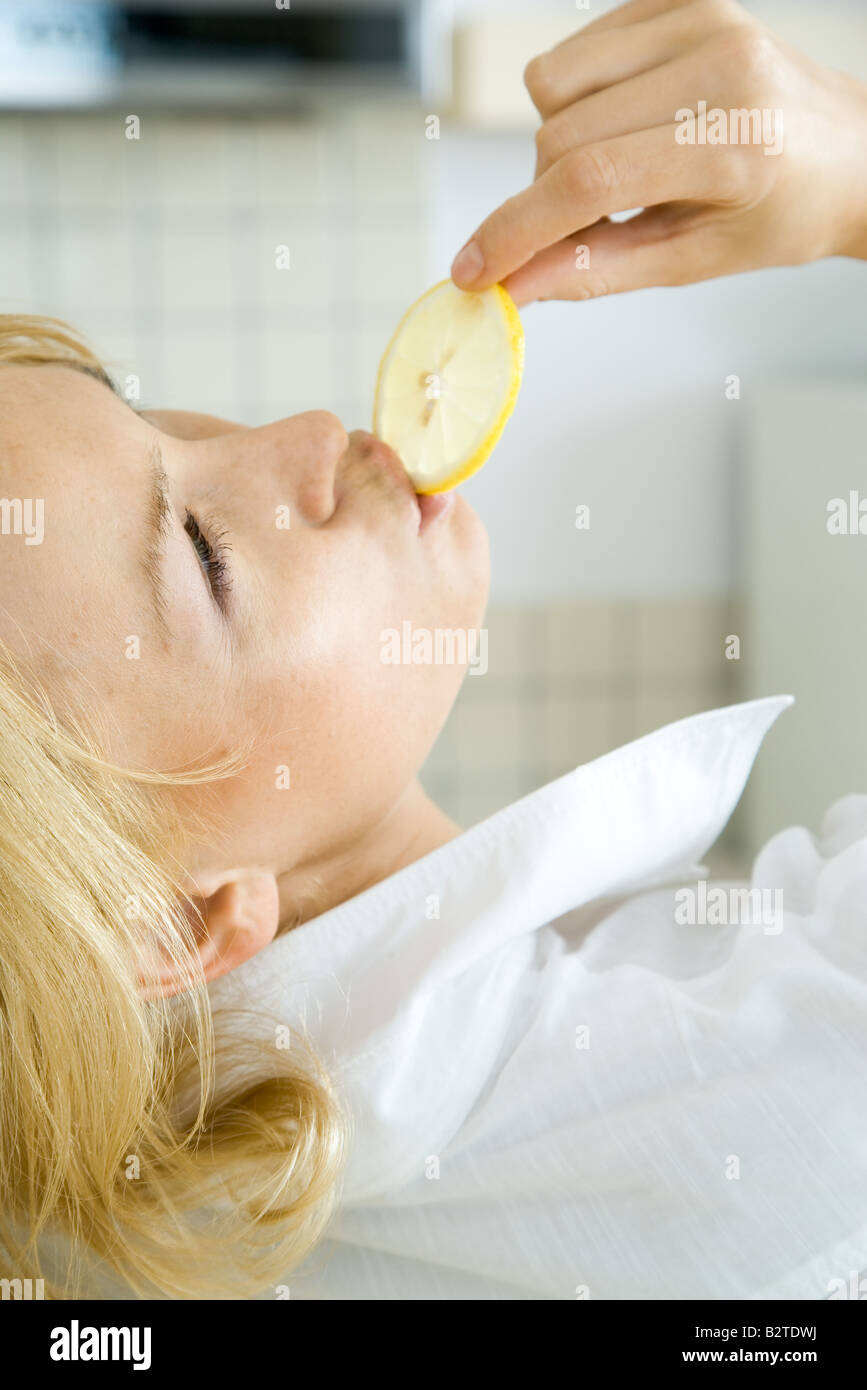 Woman eating lemon slice, head back, cropped view Stock Photo